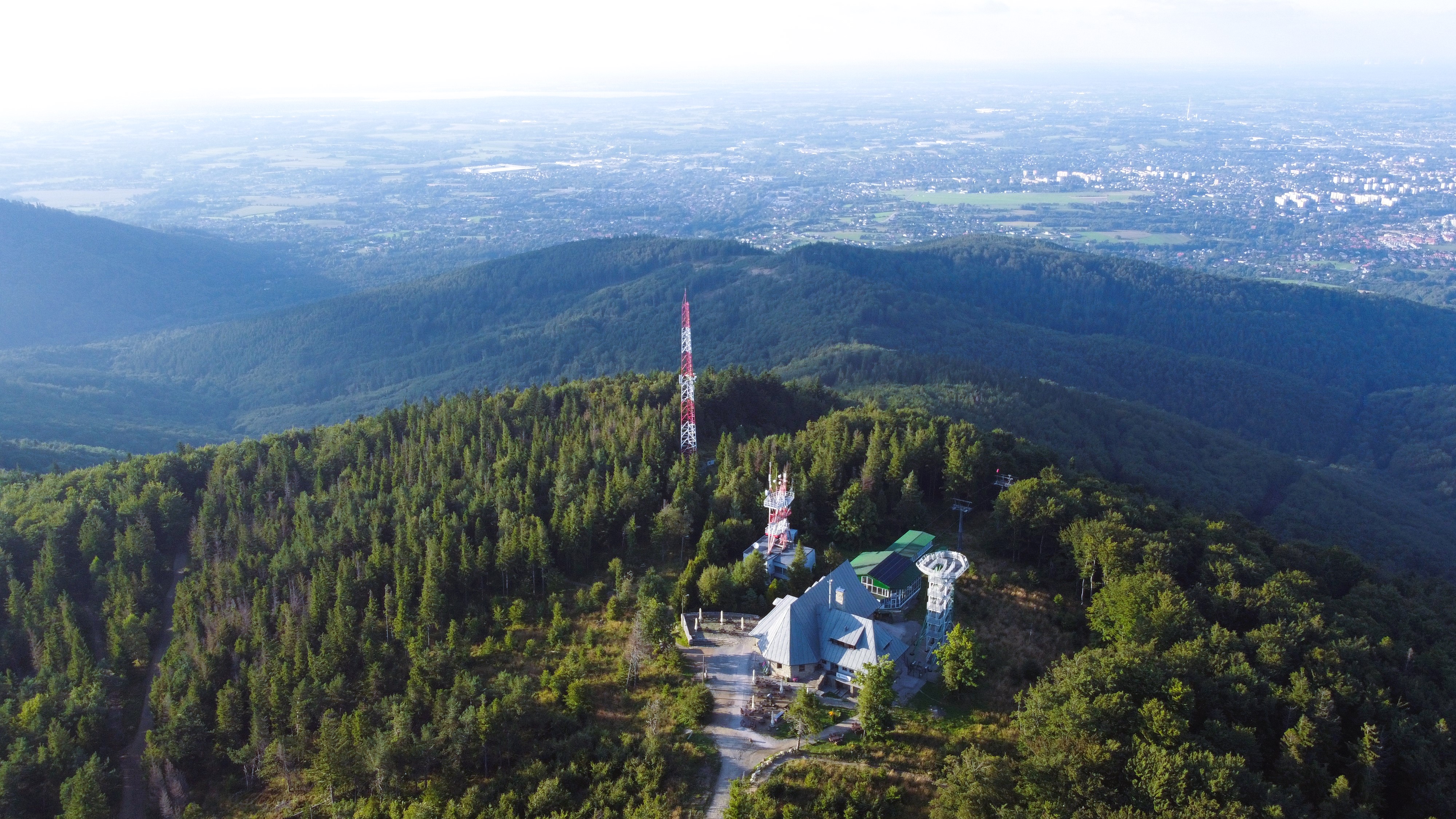 Panorama górska z zabudowaniami na szczycie góry na pierwszym planie.