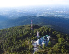 Panorama górska z zabudowaniami na szczycie góry na pierwszym planie.