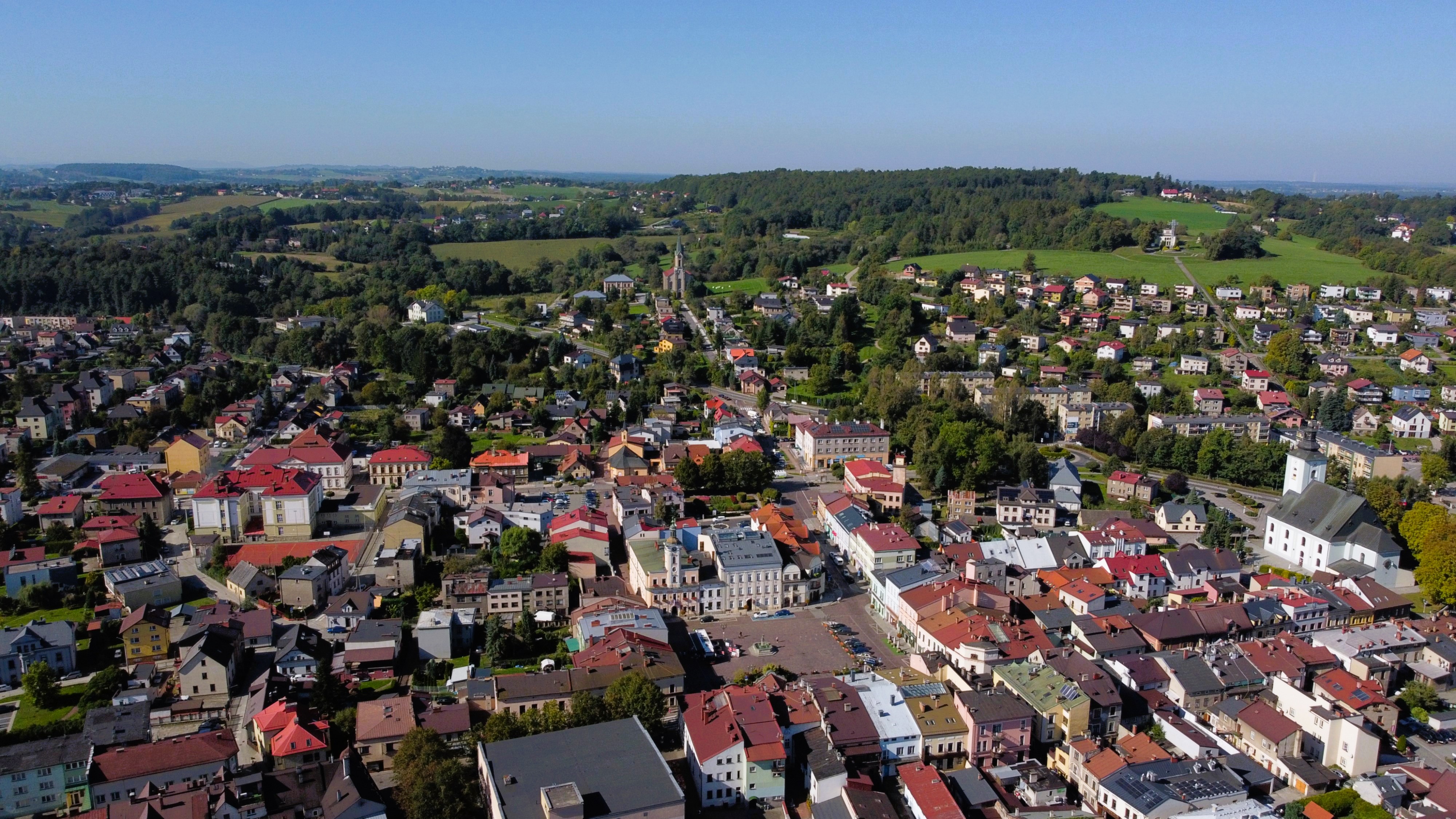 Widok z góry na zabudowę miejską z zachowanym układem historycznym, w tle zalesione wzgórza.