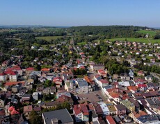 Widok z góry na zabudowę miejską  z zachowanym układem historycznym, w tle zalesione wzgórza.