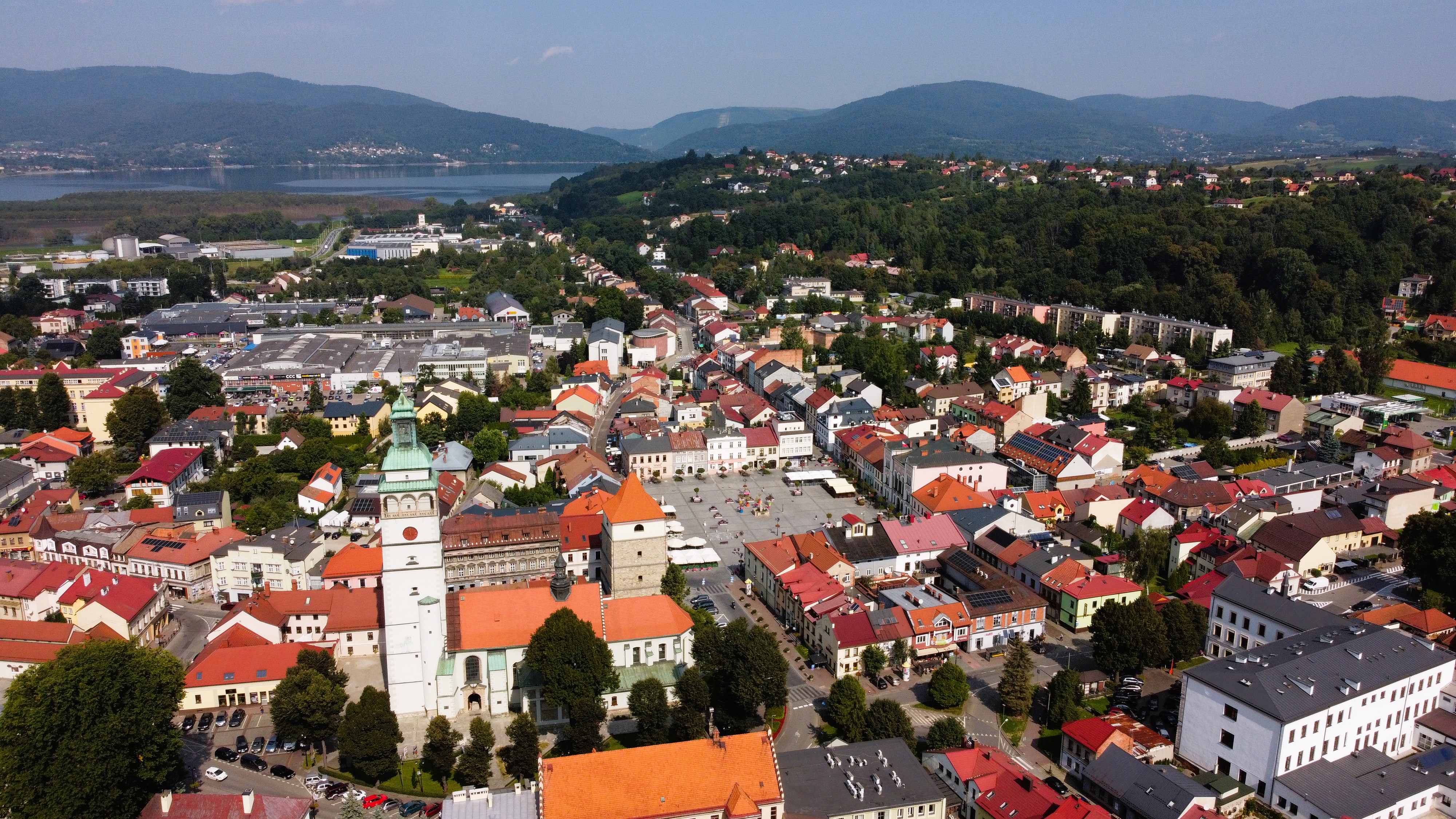 Widok z góry na zwartą zabytkową zabudowę miejską, w tle zbiornik wodny i góry.