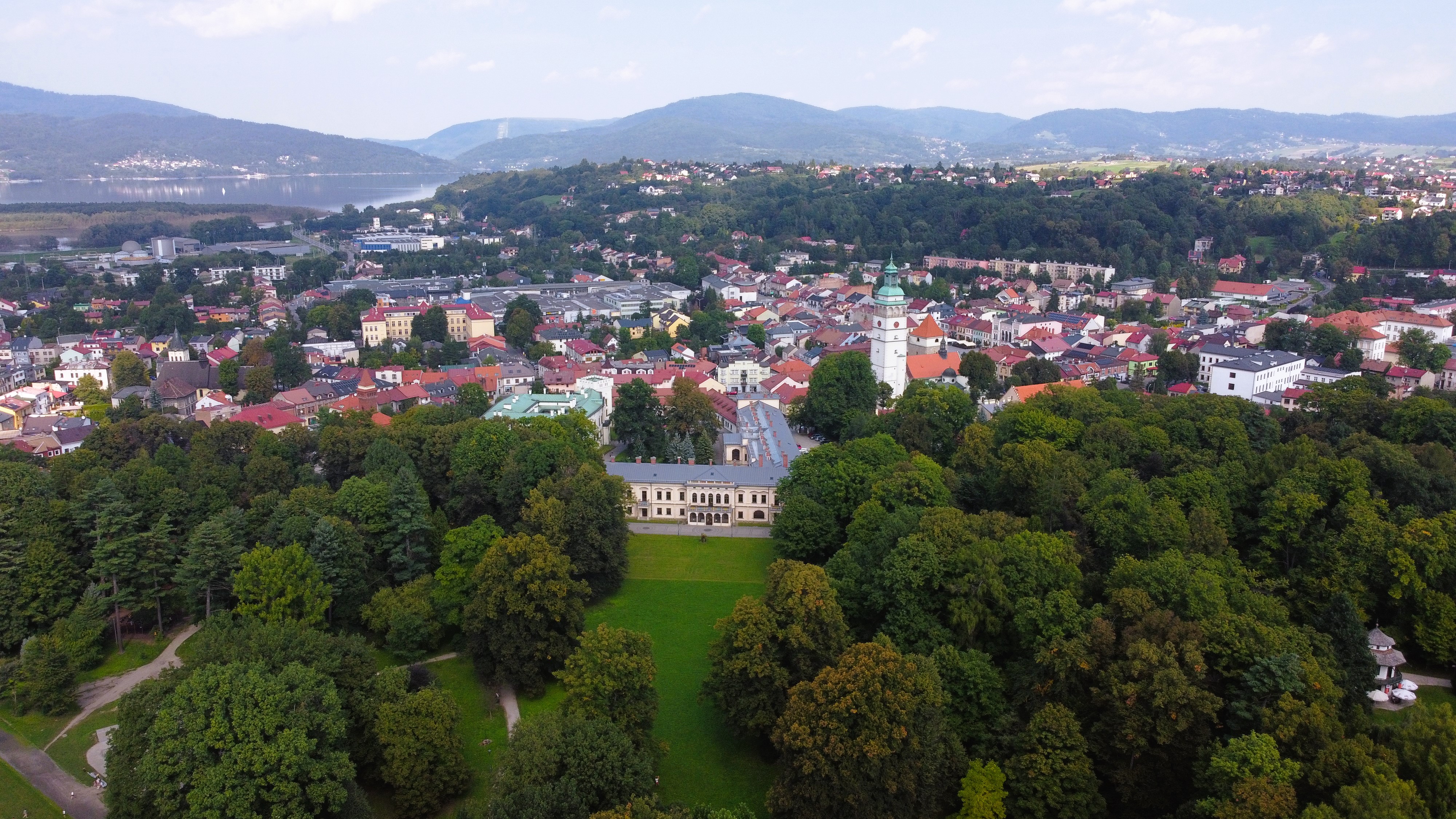 Widok w góry na zespół pałacowo-parkowo-klasztorny, zabudowa historyczna, w tle szczyty górskie.